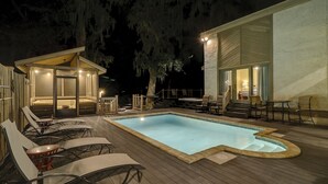 Zona junto a la piscina con sillas de descanso, bañera de hidromasaje y una zona de estar cubierta con vistas a la piscina.
