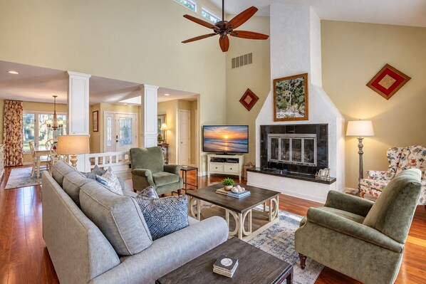 A spacious living room with a fireplace, comfortable seating, and a television.