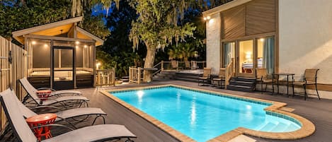 A swimming pool with lounge chairs and a covered seating area.