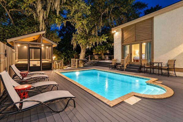 A swimming pool with lounge chairs and a covered seating area.