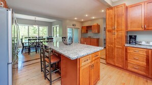 A spacious kitchen with wooden cabinets, a granite countertop, and a dining area with a table and chairs. - Deep Creek Gem w/ Views, Fire Pit & Pool Table (OAKLAND)