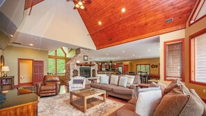 A spacious living room with a stone fireplace, leather recliner, and a large sofa.
