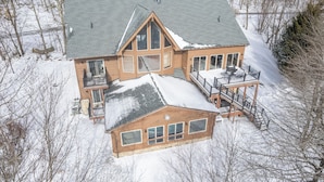 A large, two-story house with a steeply pitched roof, multiple windows, and a balcony.