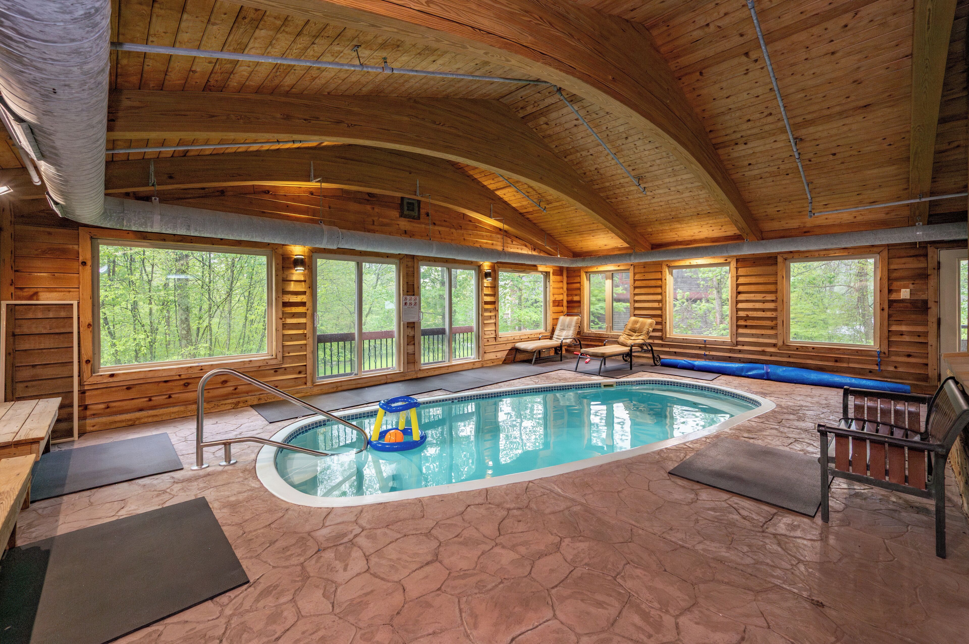 A wooden cabin with a swimming pool, large windows, and a bench.
