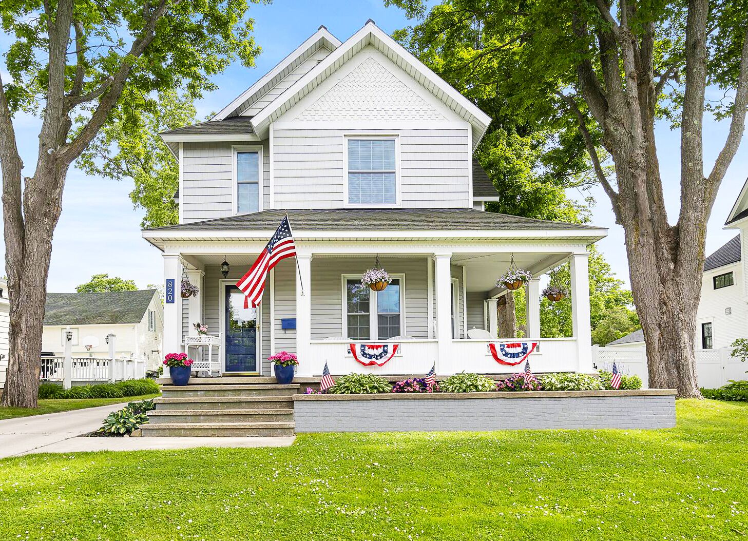 Ein zweistöckiges Haus mit Veranda, einer amerikanischen Flagge und patriotischer Dekoration.