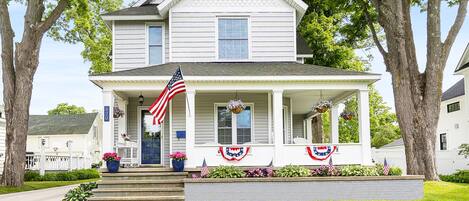 Ein zweistöckiges Haus mit Veranda, einer amerikanischen Flagge und patriotischer Dekoration.