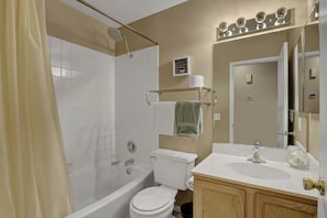 Un baño con ducha, inodoro, lavabo y espejo.