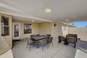Eine überdachte Terrasse mit Tisch, Stühlen, einer Tür und Fenstern.