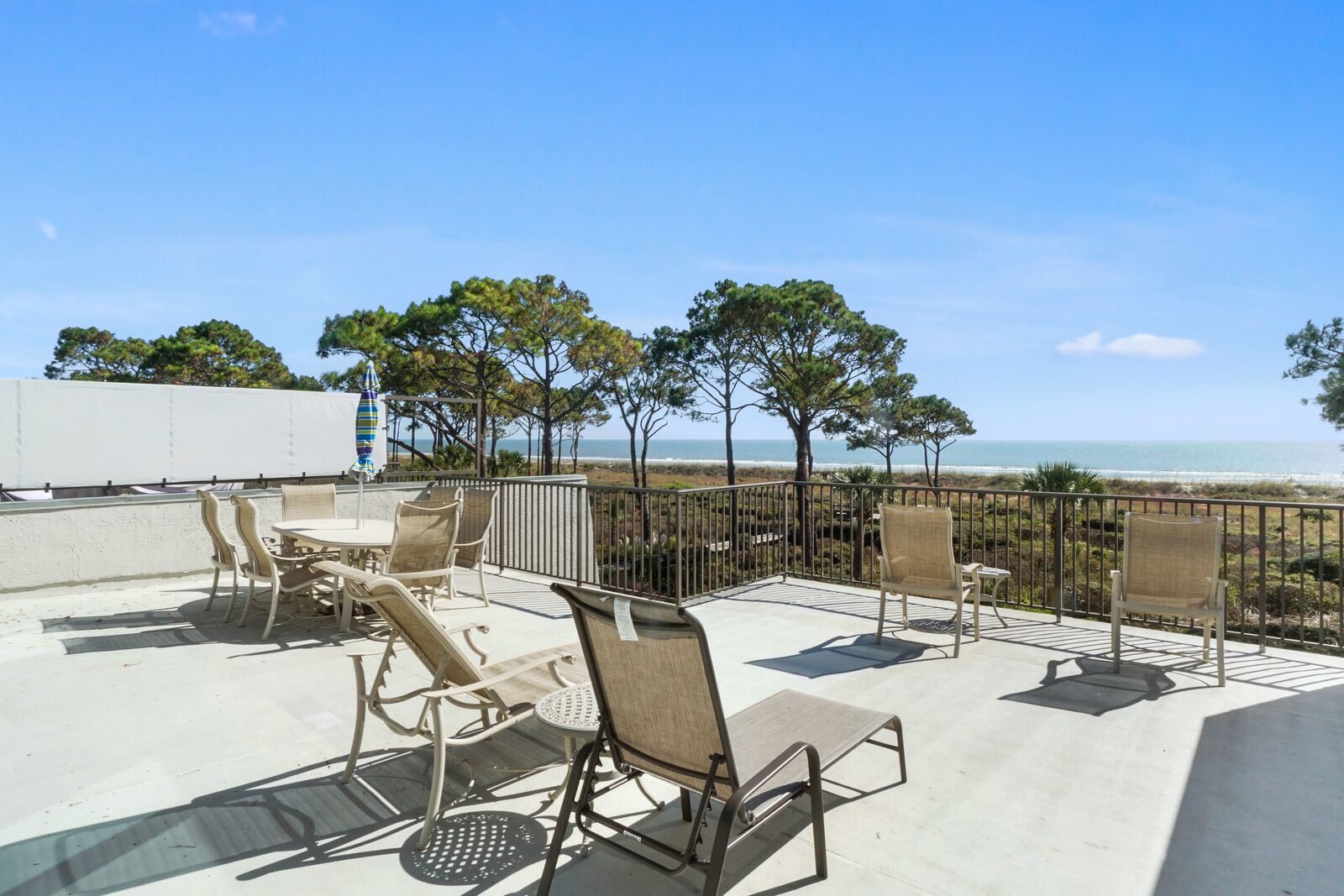 A rooftop terrace with outdoor seating and a view of the beach.