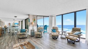 A spacious living room with a large window overlooking the ocean, furnished with multiple chairs and a wooden coffee table. - BeachFront for 8~Remodeled~Pool~2BR Edgewater 611 Tower 2 (Panama City Beach)