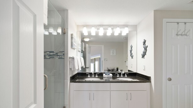 Une salle de bain moderne avec deux lavabos, un grand miroir et une douche.