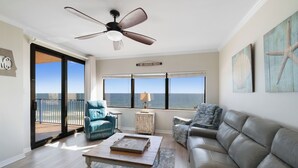Un saló amb vista a l'oceà, un ventilador de sostre i una finestra gran.