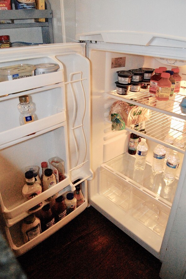 A refrigerator with multiple shelves containing various food items and beverages. - Private Suite in transitional O4W. (Atlanta)
