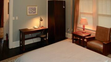 A bedroom with a bed, a desk with a chair, a lamp, and a window with curtains.