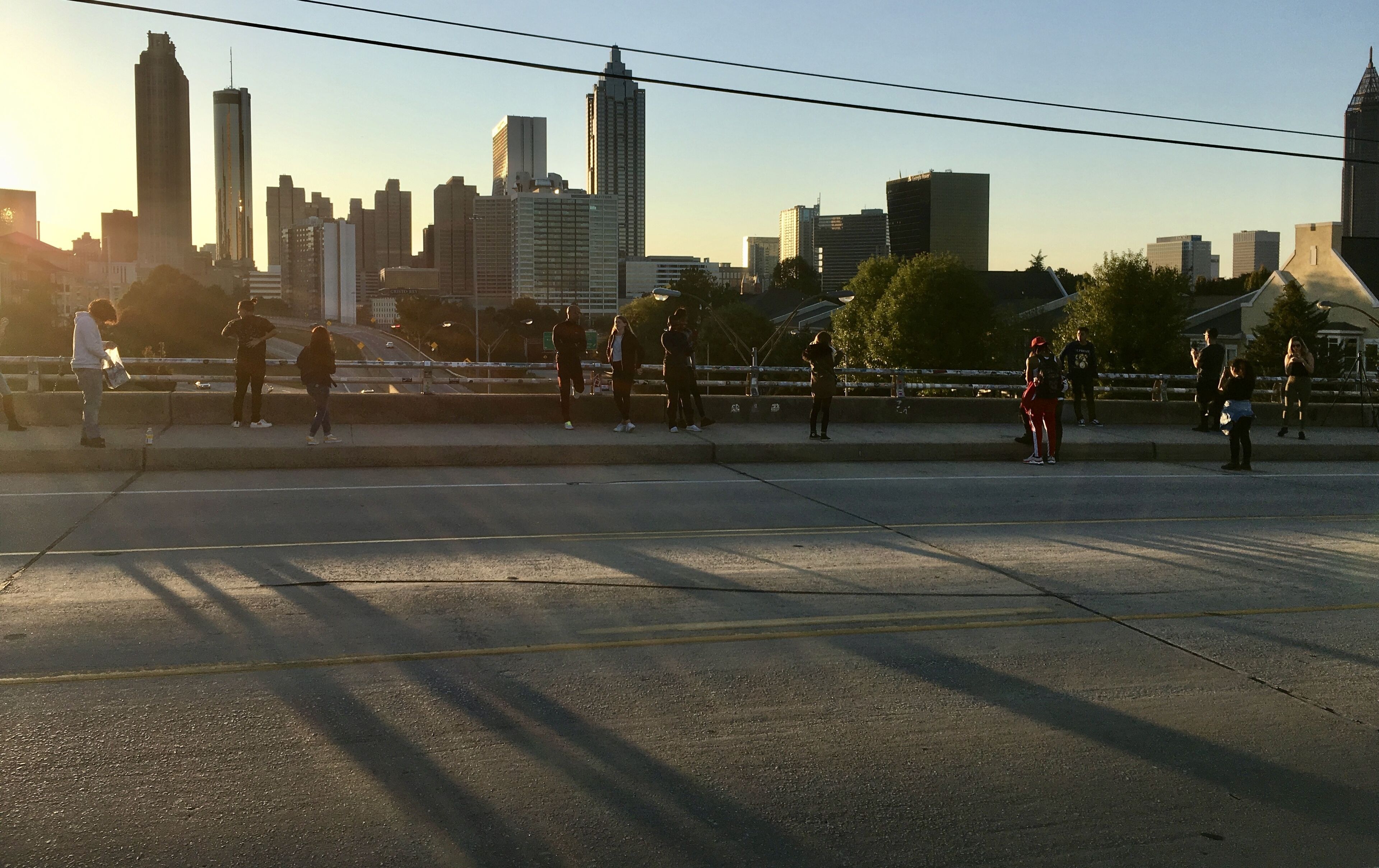 A city skyline with modern buildings and a bridge with people walking.