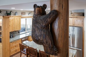 Enjoy meals in this kitchen with a wooden bear sculpture, stainless steel appliances, and a dining area.