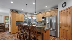 A kitchen with wooden cabinets, stainless steel appliances, and a bar area with stools.