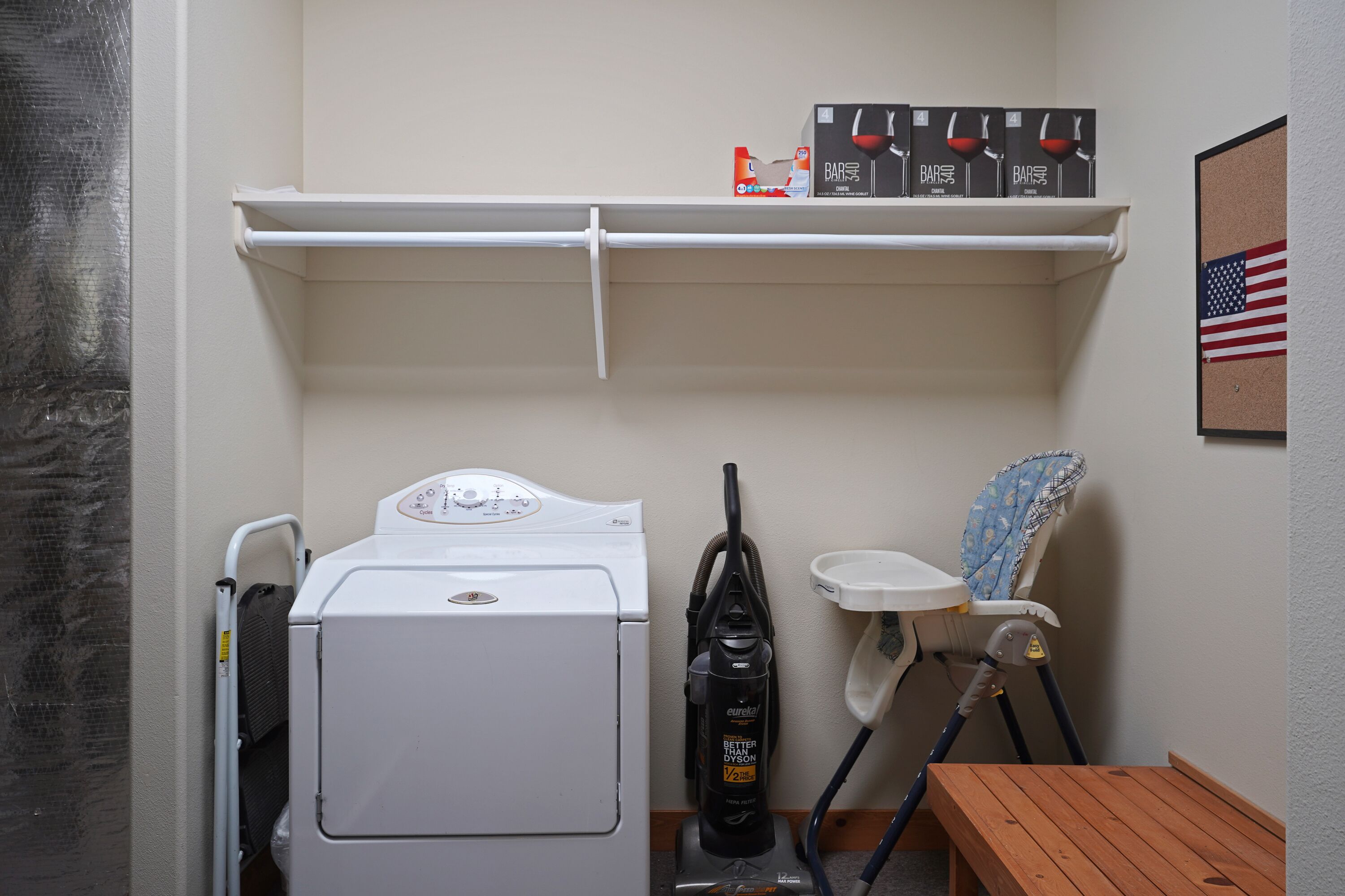 A laundry room with a washing machine, a vacuum cleaner, and a folding table.