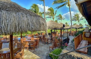 Enjoy al fresco dining under the shade of thatched umbrellas and palm trees.