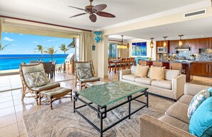 A spacious living area with a balcony overlooking the ocean, a dining area, and a kitchen. - Maui Resort Rentals Dream Collection: Honua Kai Hokulani 202 – Direct Oceanfront 3BR w/ BBQ on Wraparound Balcony (Lahaina)