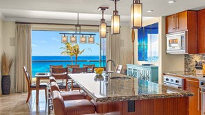 Una cocina con una isla grande, armarios de madera y vista al océano.
