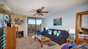 A living room with a dark-colored sofa, a wooden coffee table, and a ceiling fan.