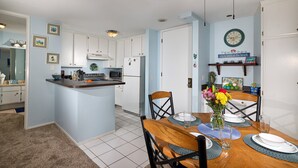 A kitchen with white cabinets, a central island, and a dining area with a wooden table and chairs.