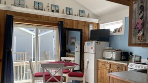 Een gezellige kamer met een bed, een eettafel met stoelen, een keuken met fornuis, koelkast en magnetron, en een balkon met uitzicht.