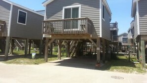 Een rij houten huizen met terras, met een centrale trap naar een balkon.