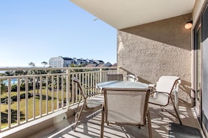 Enjoy the view of the neighborhood and water from this balcony with a table and chairs.