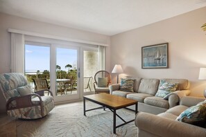 Relax in a spacious living room with a sofa set, coffee table, and comfortable seating area leading to an ocean-view balcony.