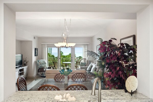 A modern kitchen with a dining area, large windows, and a view of the ocean.