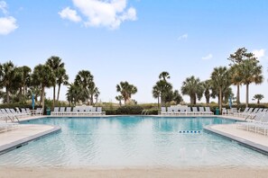 A swimming pool with lounge chairs and palm trees.