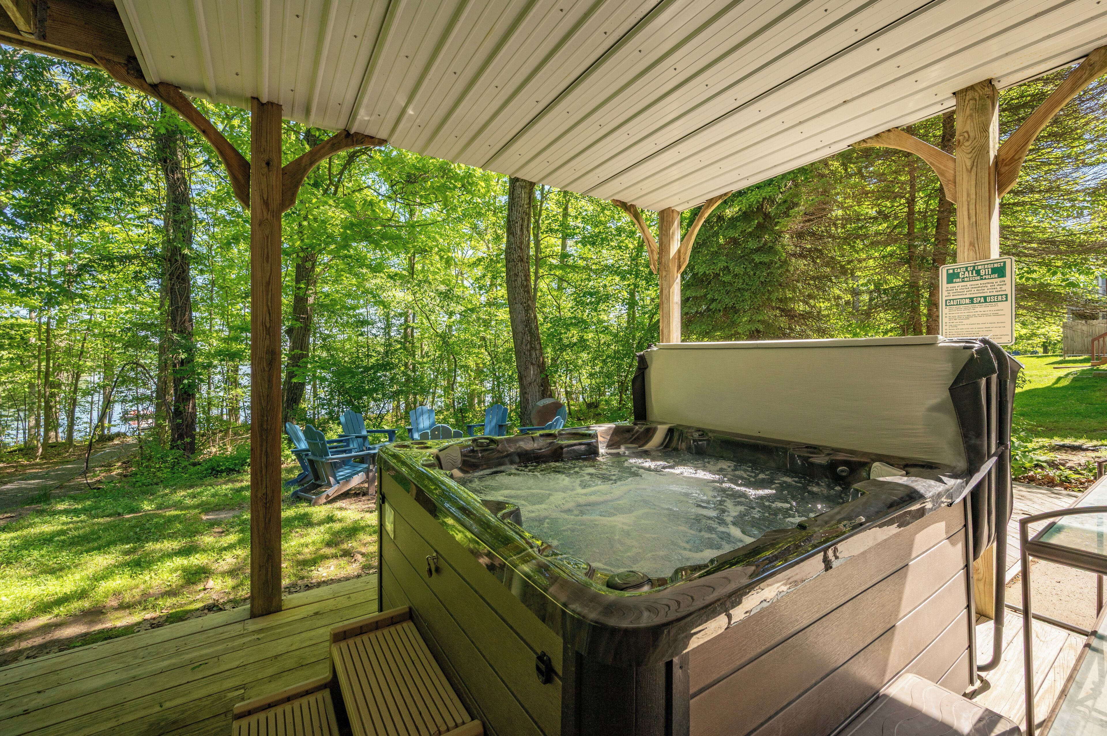 A hot tub under a wooden pergola with a sign indicating emergency procedures.