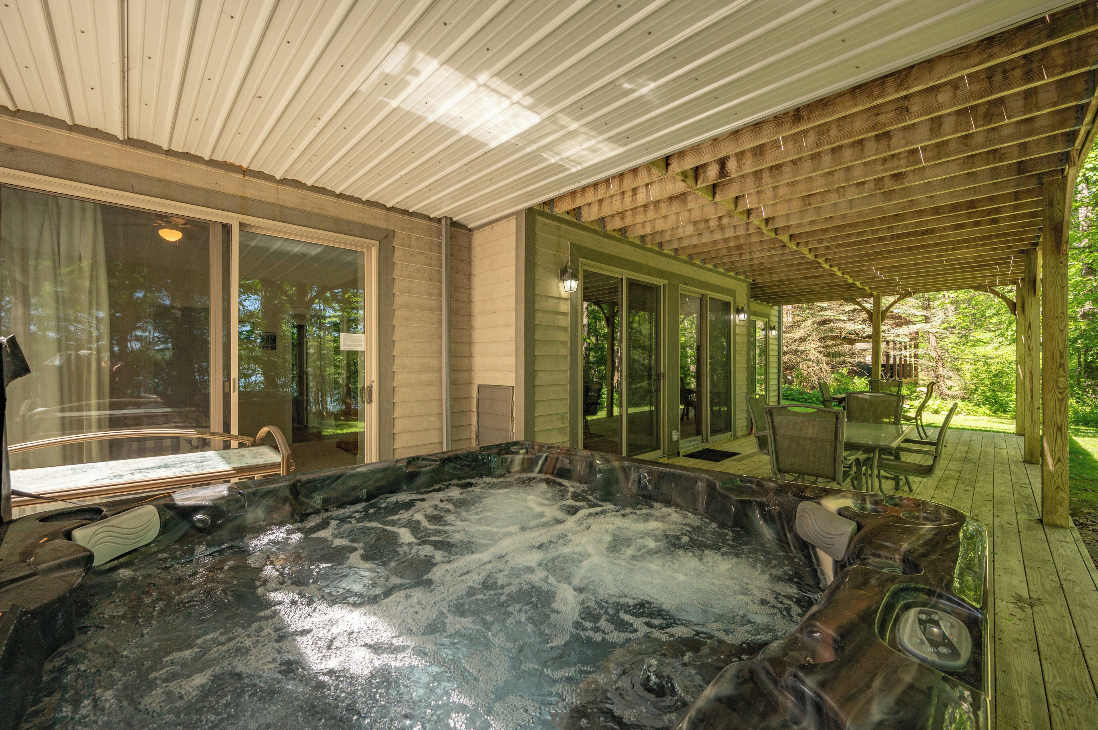 A hot tub area with a wooden deck and glass doors leading to an outdoor space.
