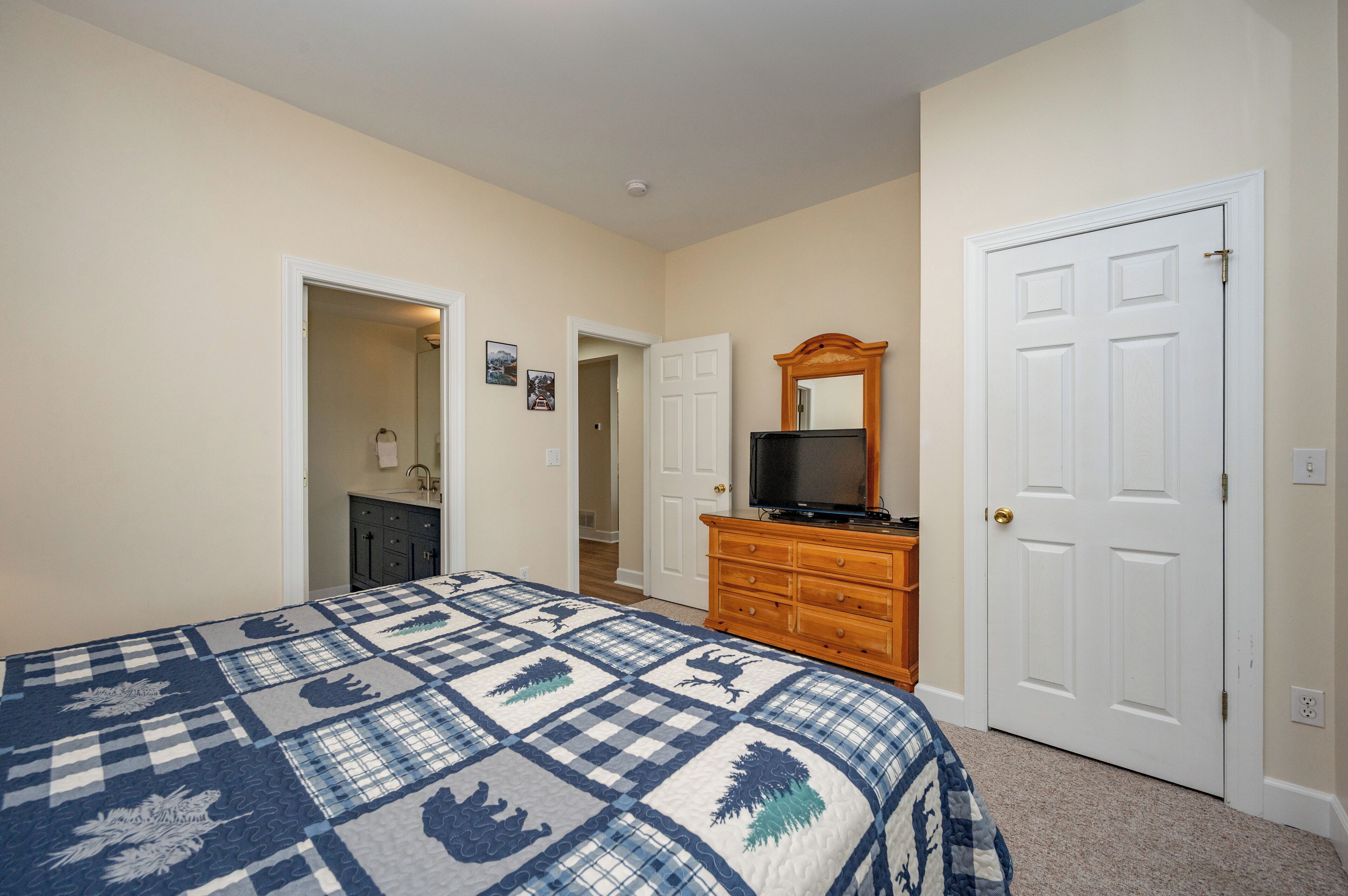 A bedroom with a bed, dresser, mirror, and two doors.
