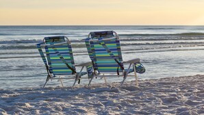 Zwei Strandstühle mit gestreiften Kissen, die zum Meer blicken.