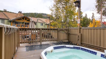 Ein Whirlpoolbereich mit Holzterrasse, umzäunter Terrasse und Blick auf Häuser im Hintergrund.