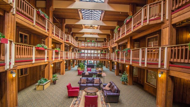 A spacious lobby with wooden architecture, multiple balconies, and a central seating area with sofas and a coffee table. - Atrium Bluebird Condo: Great Downtown Breck Location (Breckenridge)