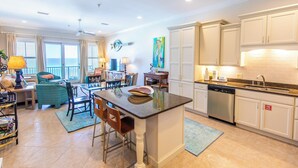 A spacious living area with a dining table, chairs, and a view of the ocean.