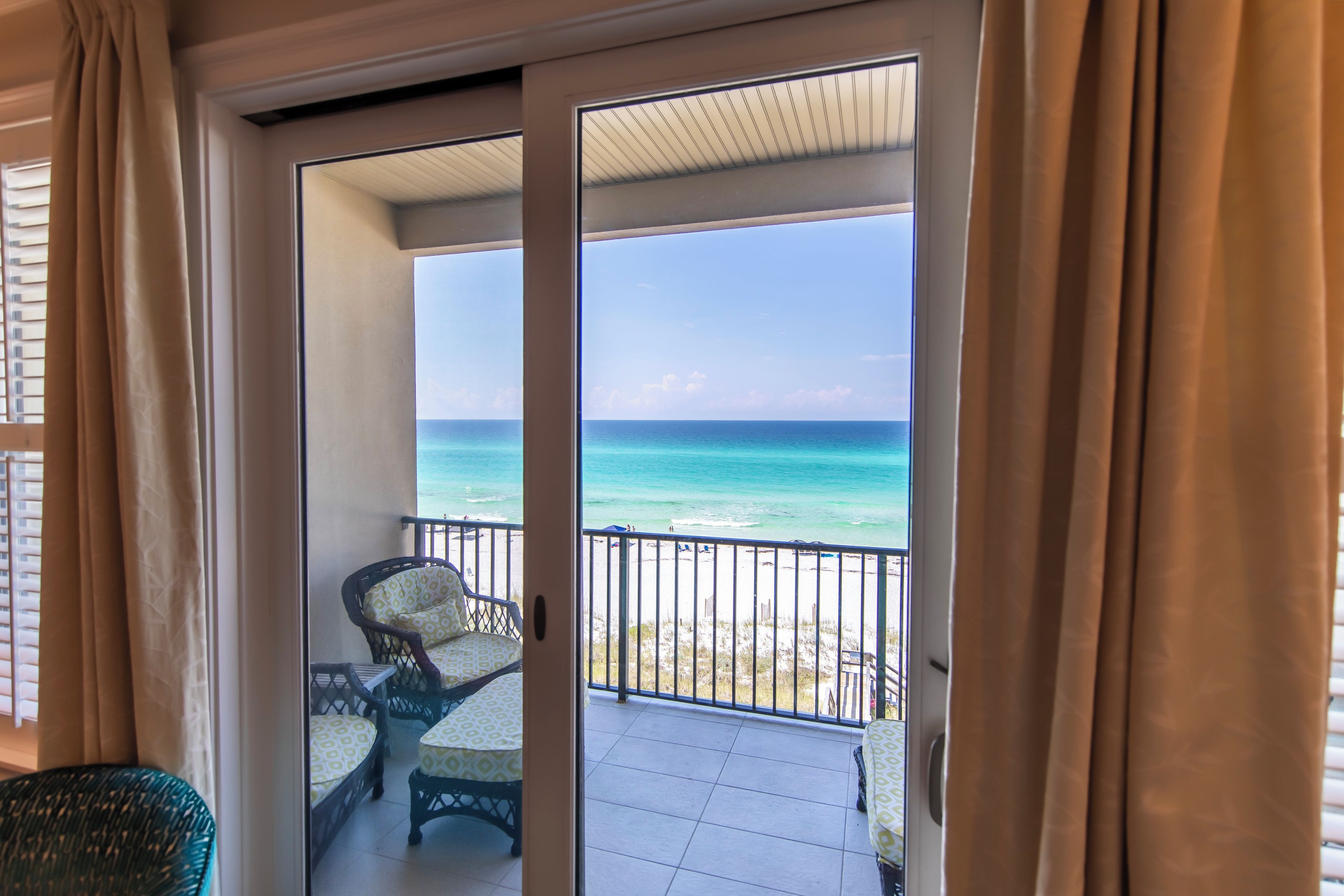 A balcony with a view of the ocean, a chair, and a table.