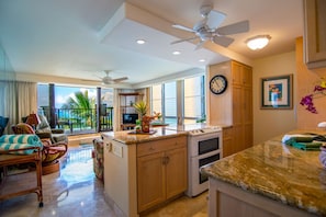 A spacious living area with a balcony, a kitchen with a built-in oven, and a dining area.
