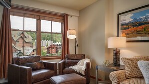 Un salón acogedor con sofás de cuero, una lámpara y vistas a edificios.