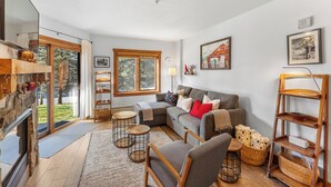 A cozy living room with a fireplace, a sofa, a coffee table, and a bookshelf. - Located Close to Gondola/Shops/Dining w/ Mountain Views from Private Balcony! (Keystone)