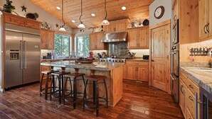 Una cocina amplia con gabinetes de madera, electrodomésticos de acero inoxidable y una isla grande con taburetes de bar.