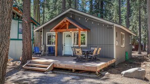 A cabin with a porch, outdoor seating, and a small deck.