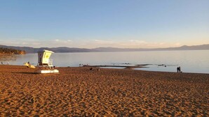 Ein Strand mit einem Rettungsturm, sandigem Ufer und einem ruhigen See.