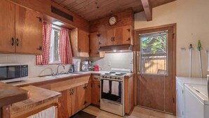 Eine Küche mit Holzschränken, einer Mikrowelle, einem Herd und einem Kühlschrank.