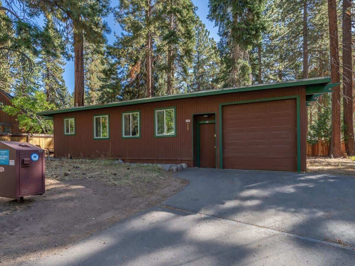 A single-story building with a garage, surrounded by tall trees.