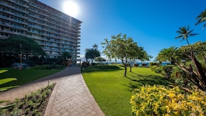 Un hôtel doté d’un grand bâtiment, d’une allée pavée et de pelouses et de plantes tropicales bien entretenues.